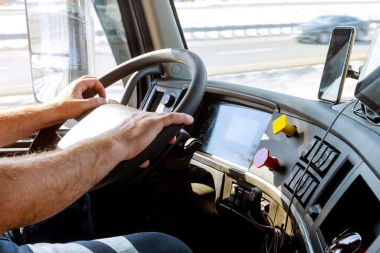 Close-up picture of a person's hands on the steering wheel of a commercial motor vehicle.