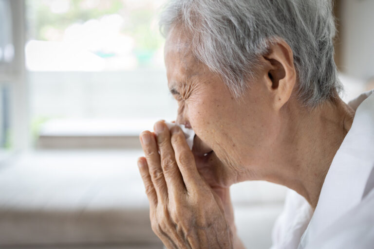 Picture of an older woman sneezing.