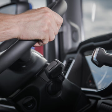 Picture of a truck driver's hands on a steering wheel.