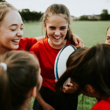 Picture of teenage girls huddling during a rugby game.