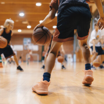 Picture of young boys dribbling basketballs in a gym.