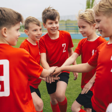 Picture of a group of young boys on a soccer team huddling during a game.